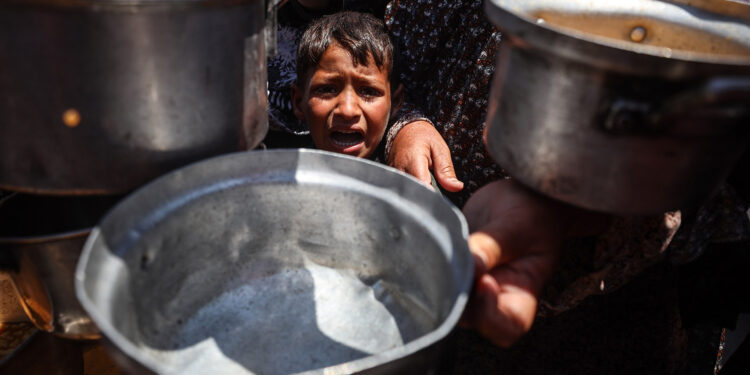 Displaced Palestinians scuffle for a portion of hot food at a charity kitchen in central Gaza City, on May 5, 2025. The humanitarian crisis in the besieged Gaza Strip worsens significantly since Israel blocks all aid from entering the territory on March 2, days before resuming its military campaign following the collapse of a ceasefire. (Photo by Majdi Fathi/NurPhoto via Getty Images)