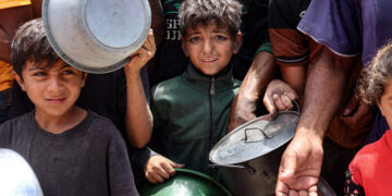 Palestinian children wait in front of a hot meal distribution truck at a displacement camp near Gaza City's port on May 22, 2025. The Israeli army issued an evacuation warning on May 22 for 14 neighbourhoods of northern Gaza, as it pressed a renewed offensive that has drawn international condemnation. (Photo by Omar AL-QATTAA / AFP) (Photo by OMAR AL-QATTAA/AFP via Getty Images)